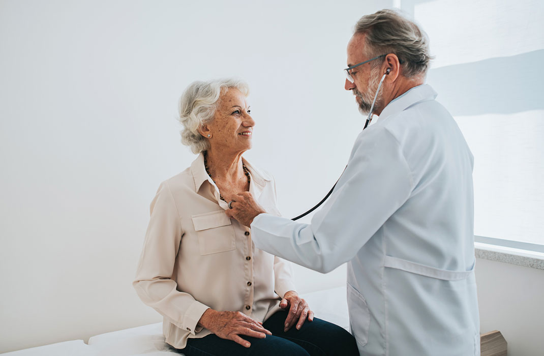 A cardiologist uses a stethoscope on a patient