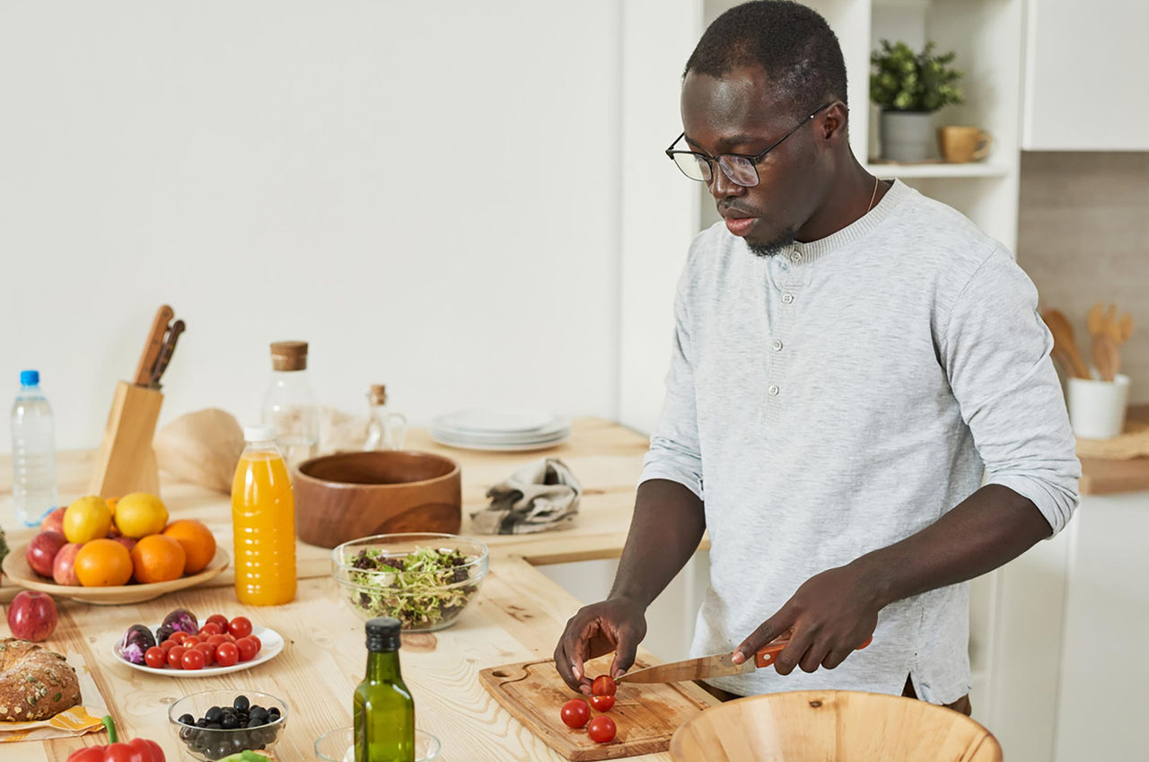 A young man prepares ingredients for a meal with fresh produce in his kitchen