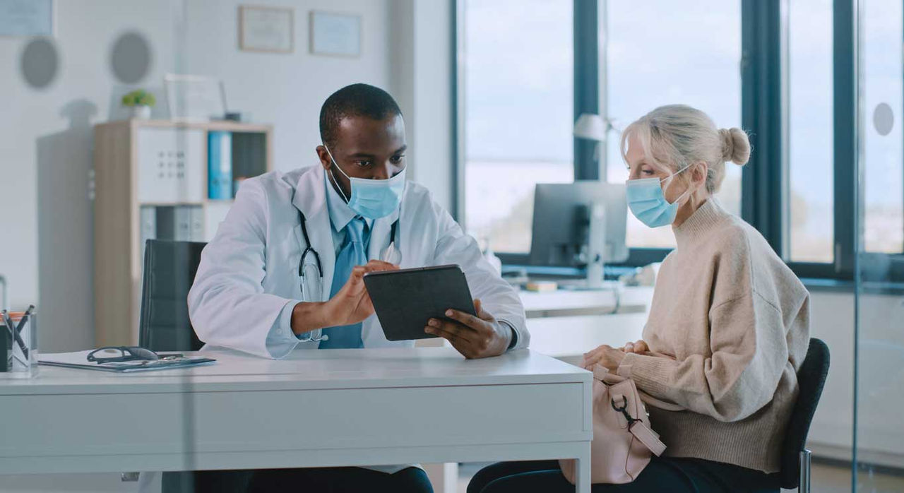 Bile duct cancer patient and doctor discuss something shown on a tablet.