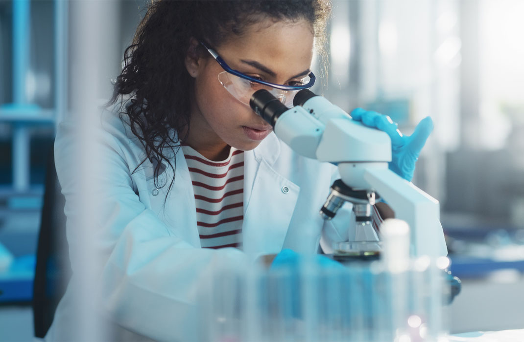 A gene and cell therapy researcher views slides on a microscope.