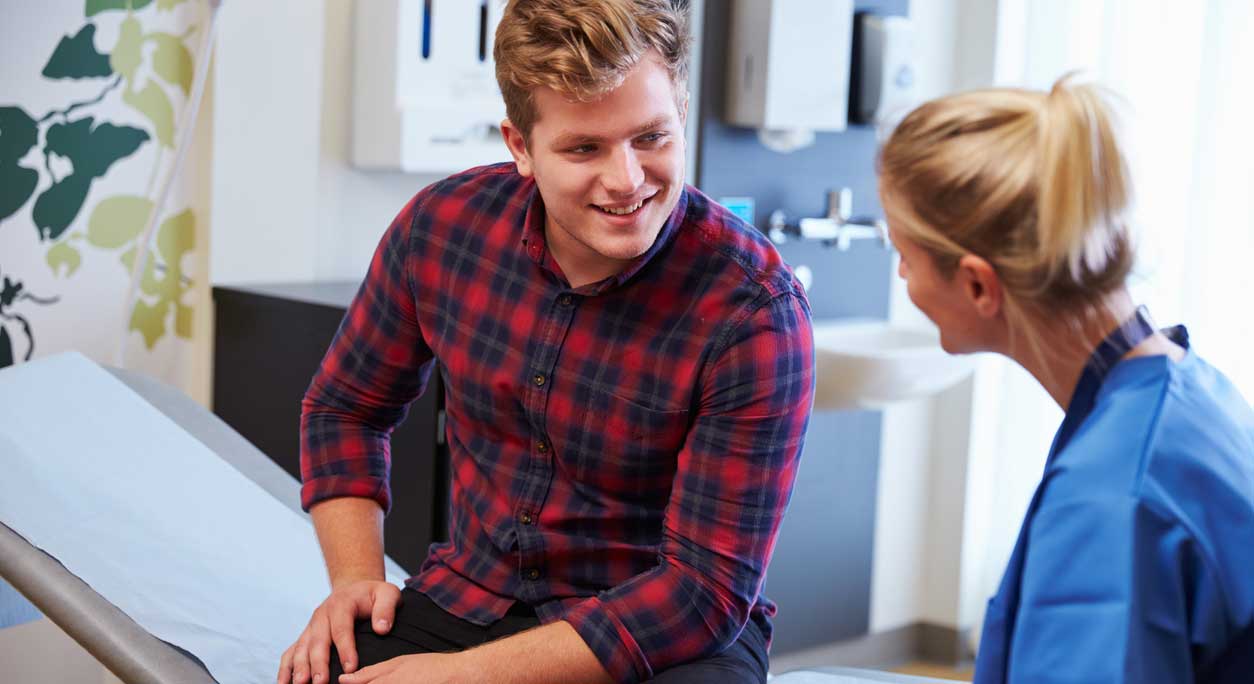 A cheerful young man discusses his symptoms with his provider.