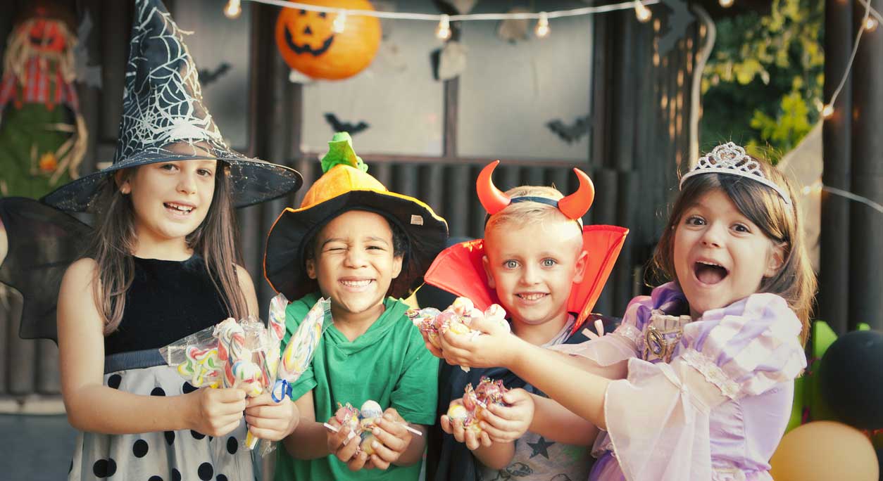 Costumed children with their hands full of candy.