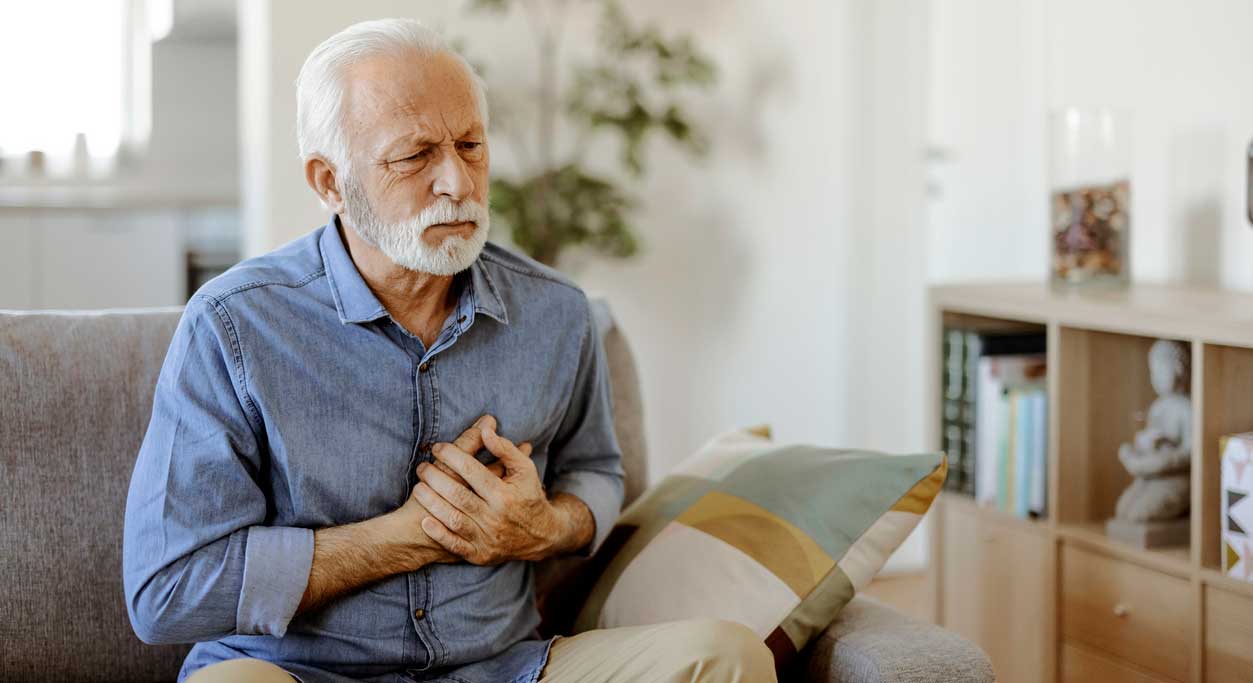 An older man holds his chest with a pained expression.