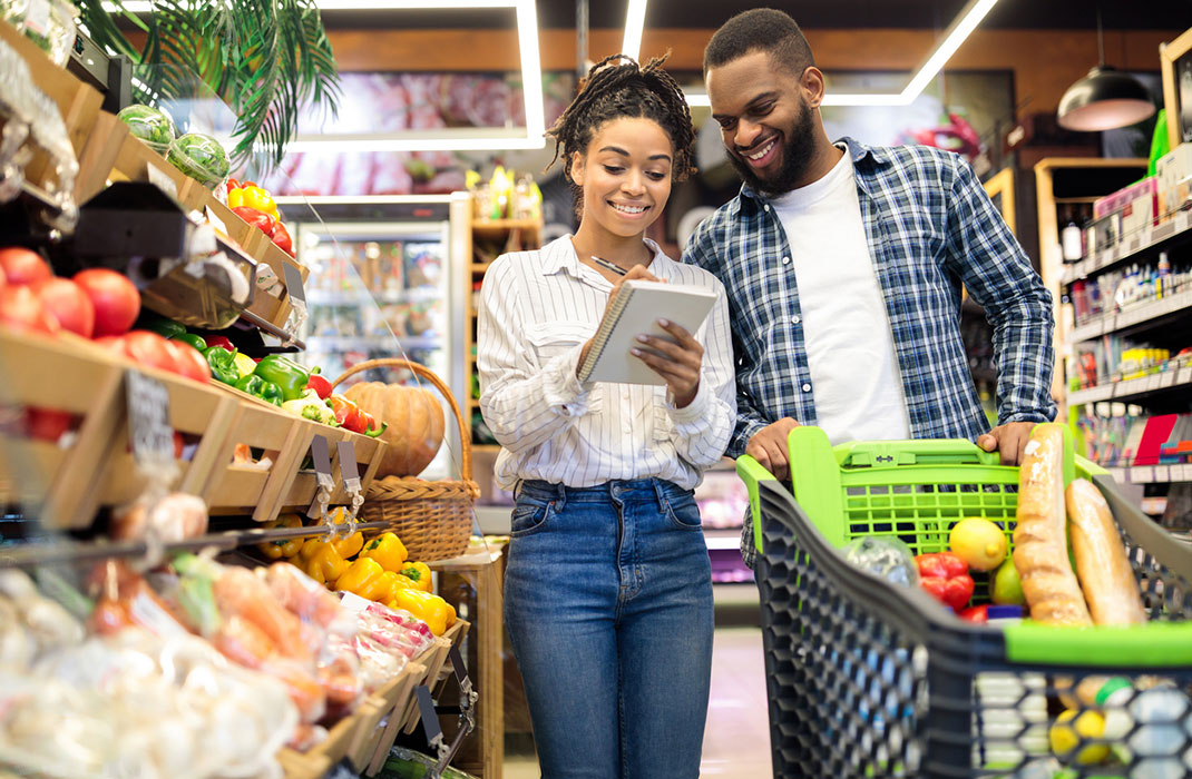 A couple checks their heart-healthy grocery list in the supermarket, shopping in the produce aisle. 