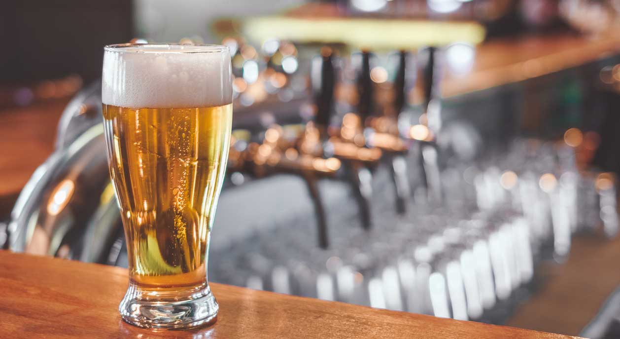 A glass of beer on a bartop.