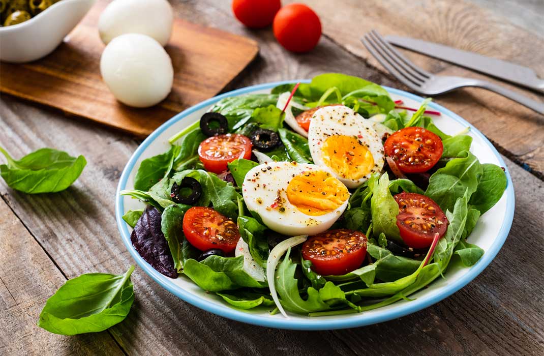 A luscious-looking salad of greens and tomatoes, topped with a soft-boiled egg.
