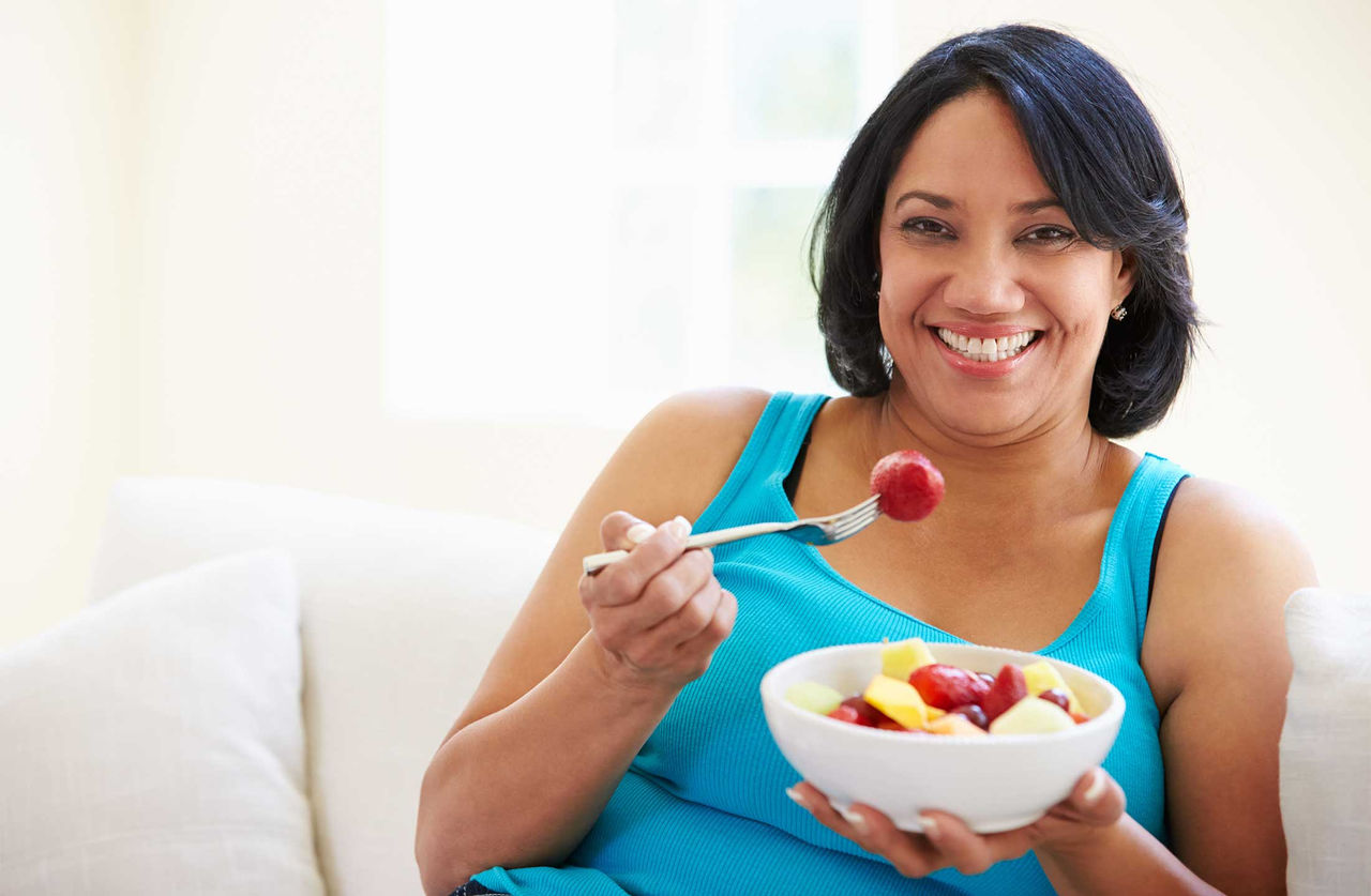 A woman eating a bowl of fruit.