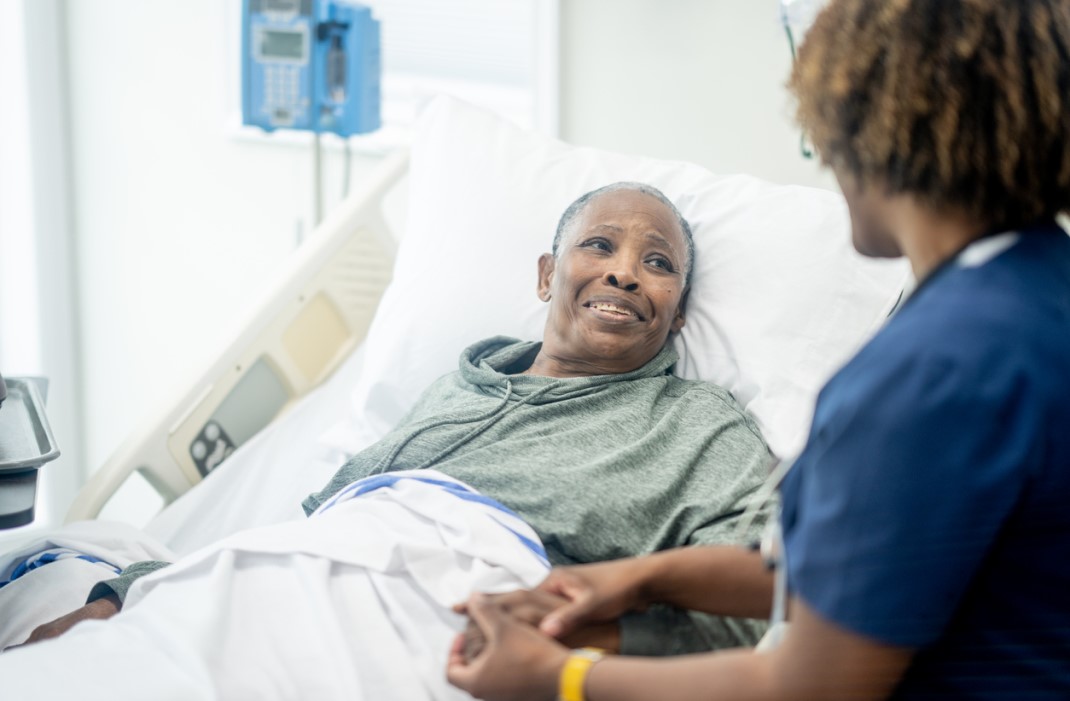 Nurse comforts older adult in hospital for surgery.