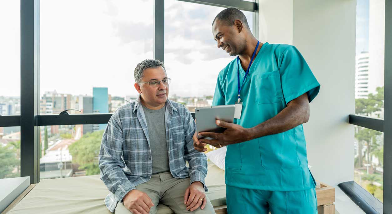 A doctor and patient discuss something displayed on a tablet screen.