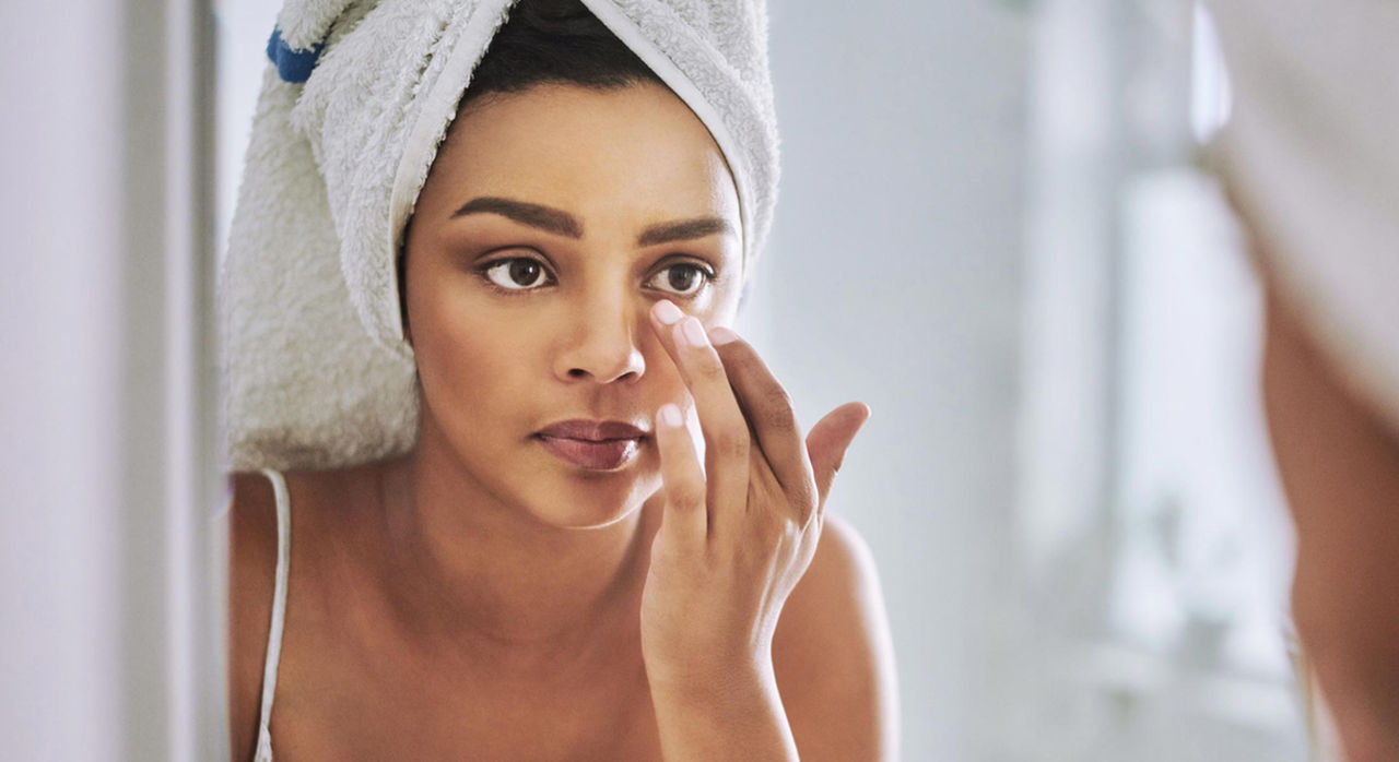 Woman applies moisturizer to her face after a shower to prevent dry skin in winter.