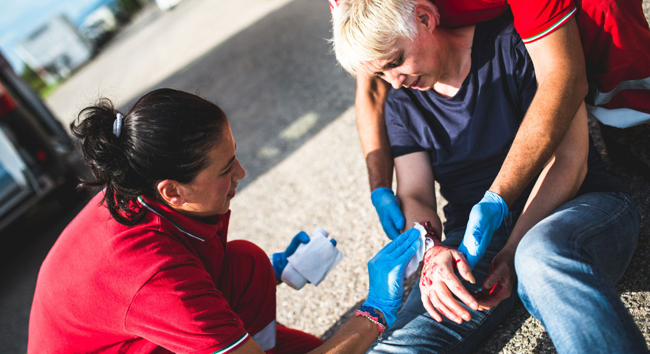 Two helpers work to stop bleeding after an accident. 