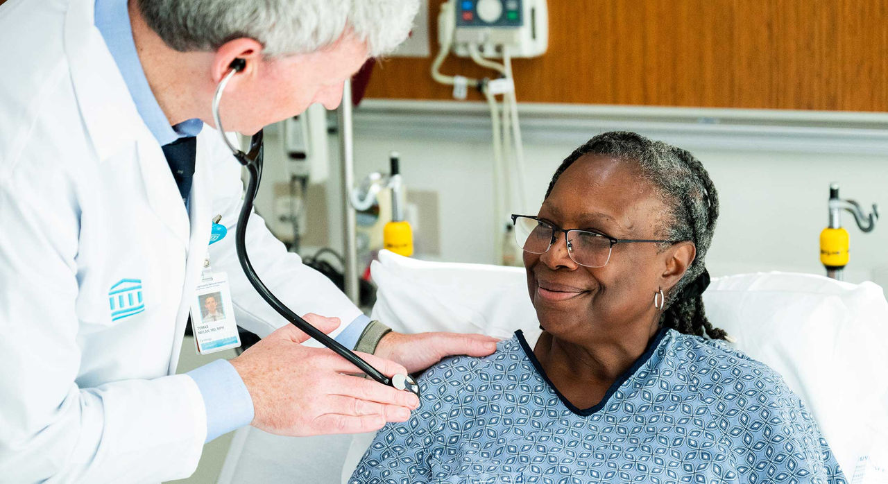 Dr. Neilan cares for a cancer patient in a hospital bed.