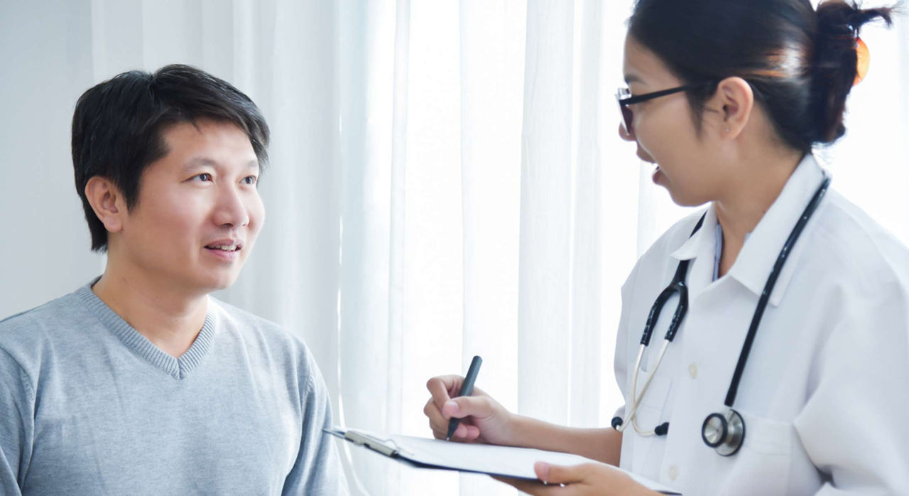 A doctor discusses a clipboard of information with a patient.