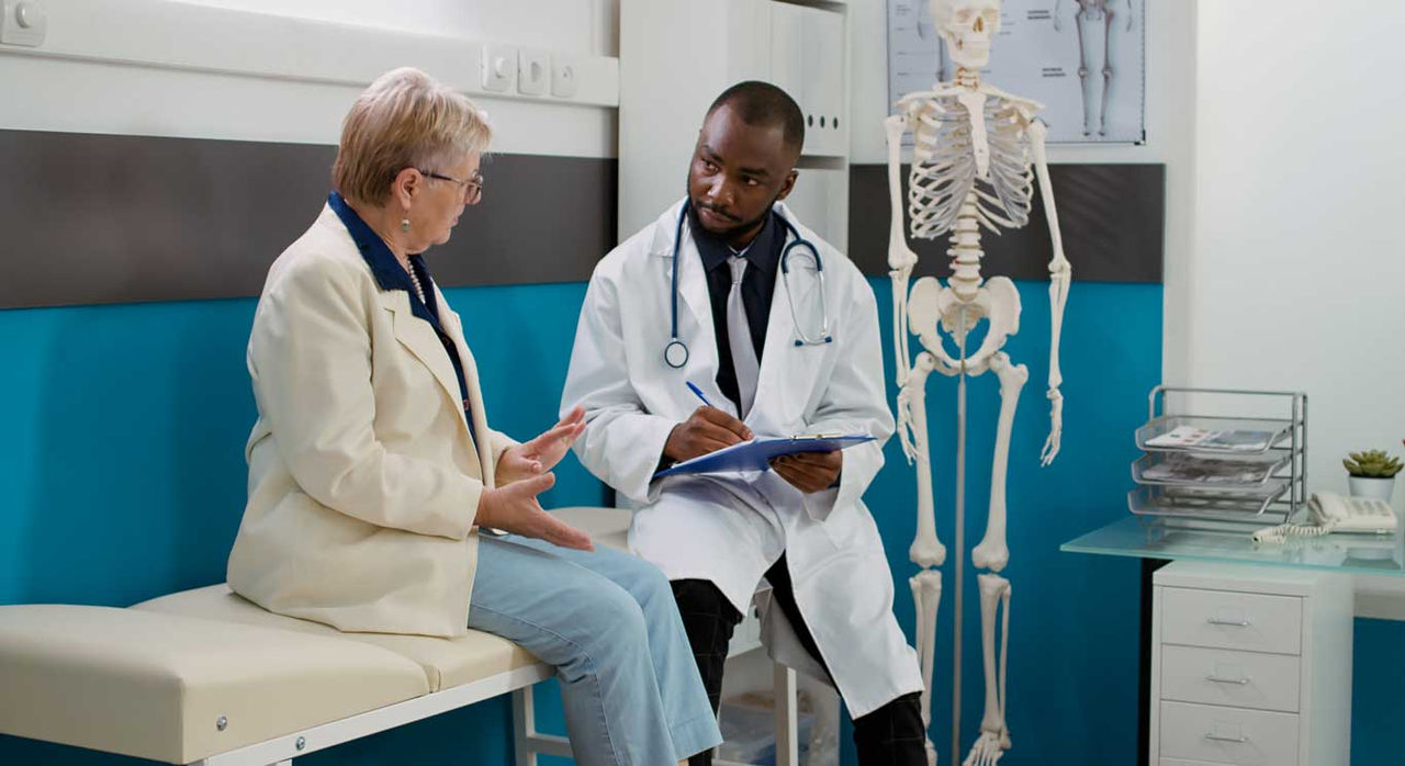 A patient speaks with her doctor about the pros and cons of knee replacement.