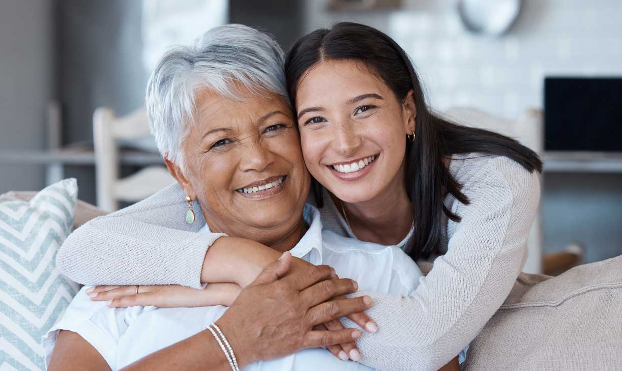 A daughter embraces her mother on the sofa.