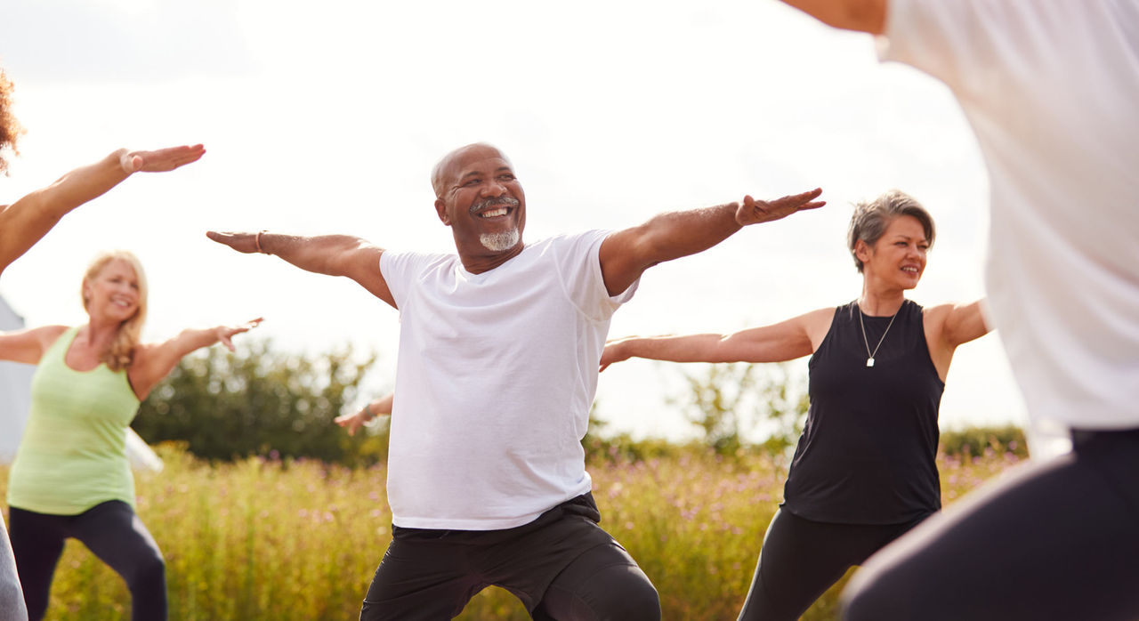 People doing yoga outdoors and smiling