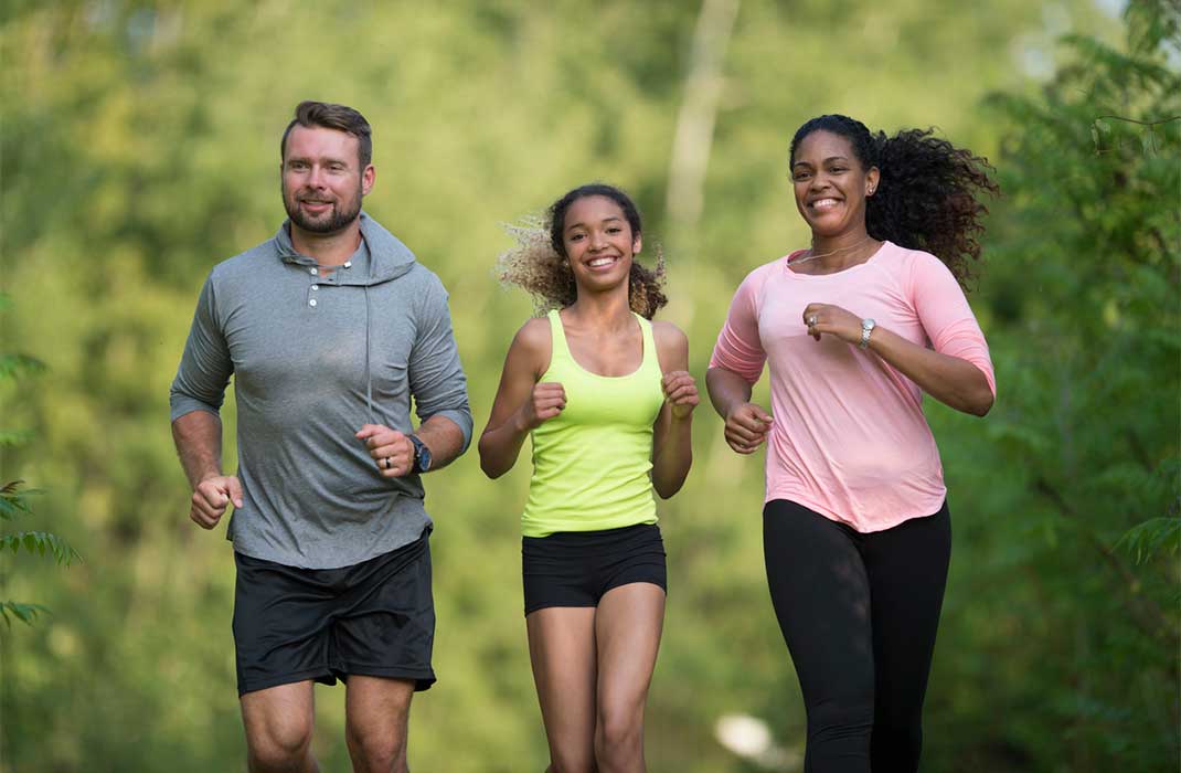 Mother, father, and teen daughter jogging together.