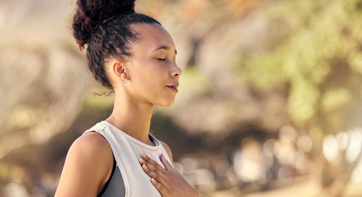 Woman meditating with hand on chest.