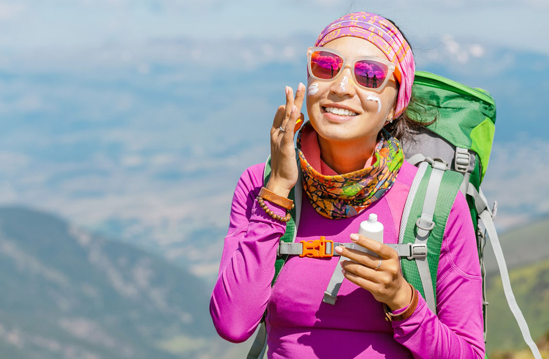 A woman hiker applying sunscreen.