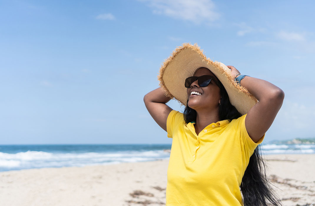 A woman wearing a hat and sunglasses to protect against skin cancer.