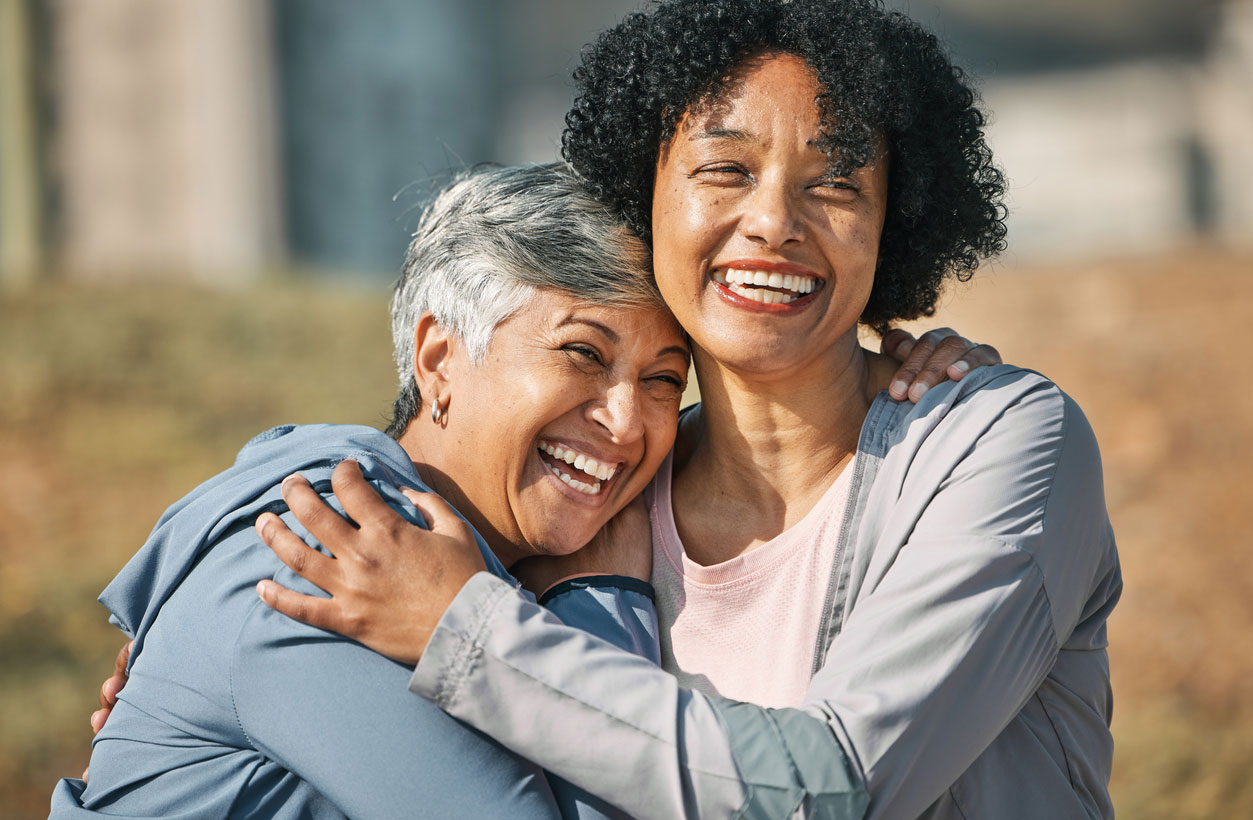 Two older women laughing and hugging each other.
