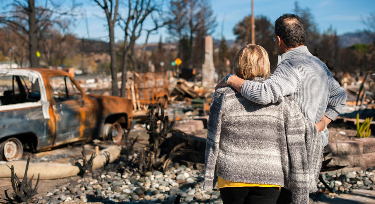 Husband and wife checking burned home after a wildfire