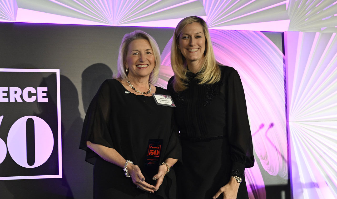 Two women in evening clothes pose with their Fierce 50  trophy.