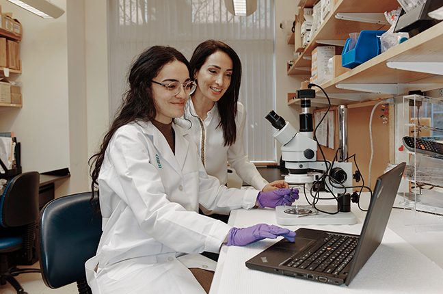 Natalie Artzi and a lab assistant review data on a computer in the lab