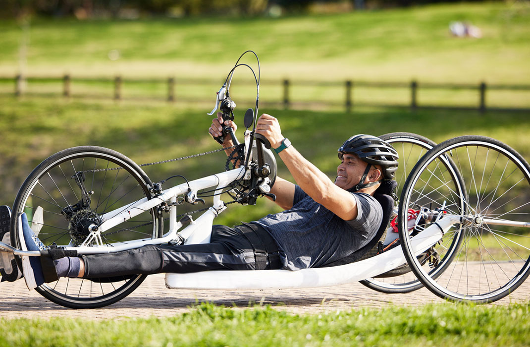 A person uses their recumbent cycle for adaptive cycling in a field.
