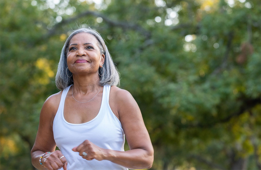 An older Black woman jogging in the park.