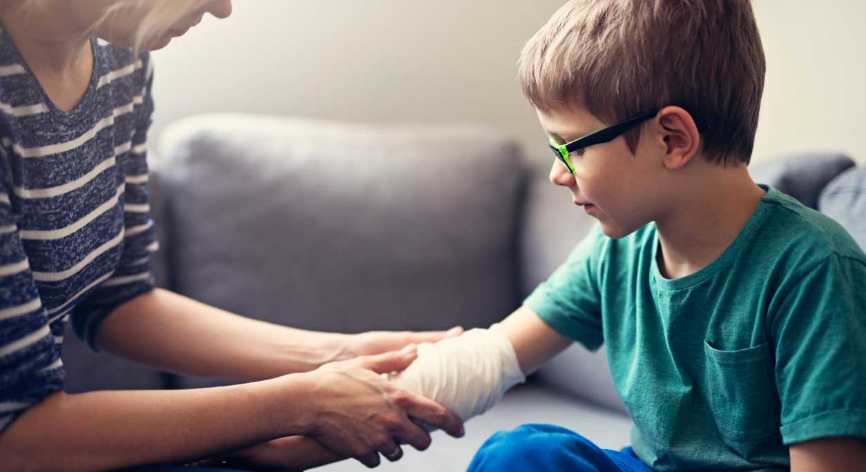 A parent puts a bandage on a child’s burn.