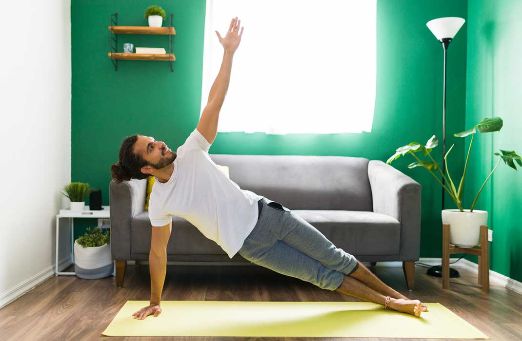 A man doing the side plank exercise in his living room.