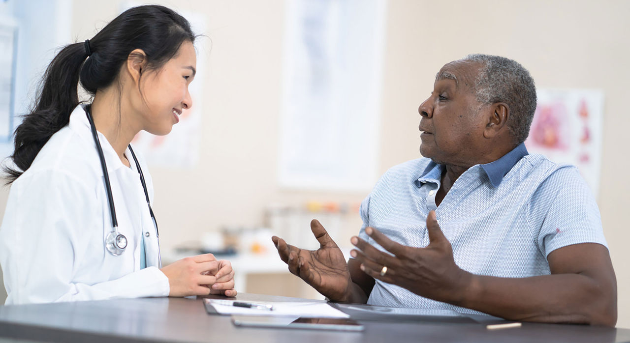 A middle-aged man discussing prostate cancer symptoms during a visit with his doctor