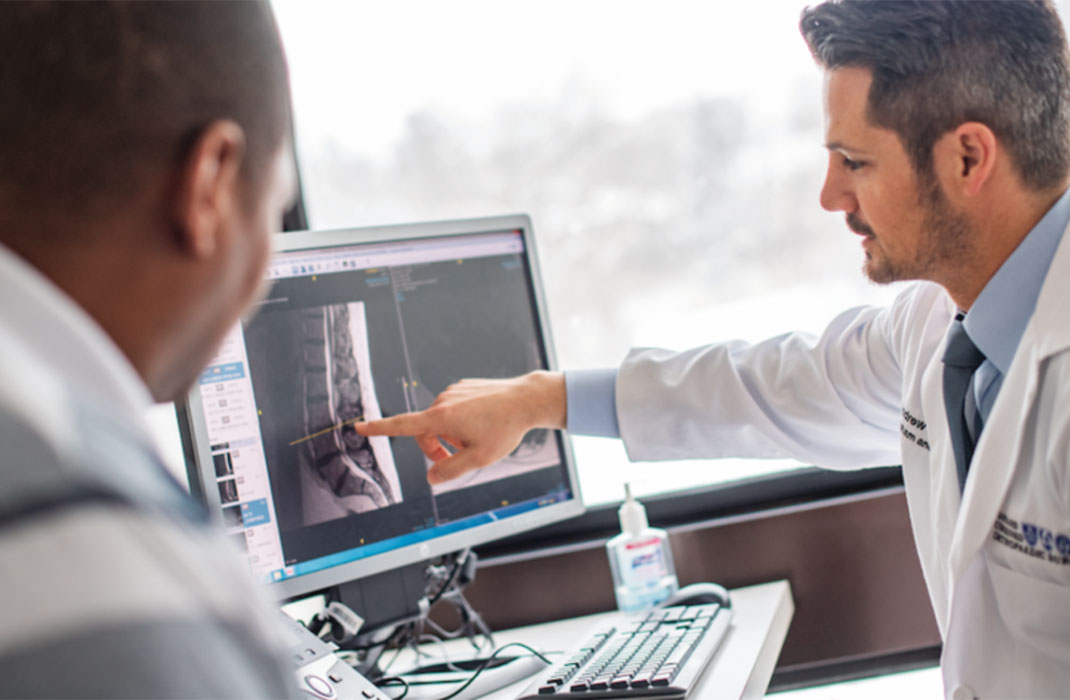 Two doctors review an x-ray image of the lumbar spine