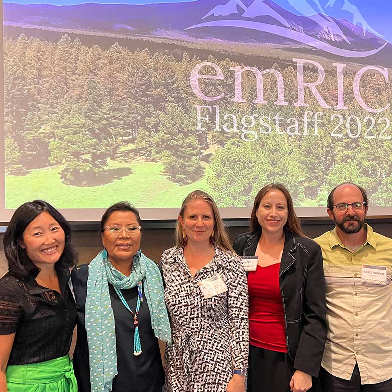 A group of five people standing in front of a presentation screen