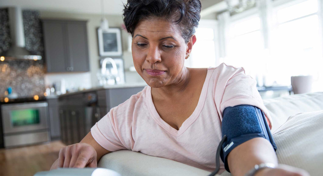 Woman using a blood pressure monitor at home.