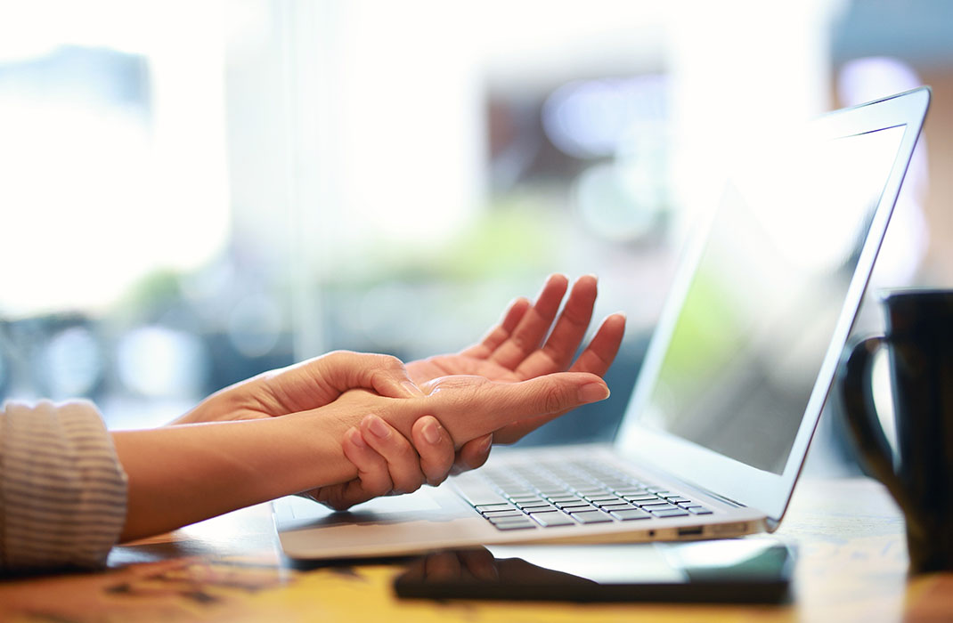 person at laptop holding the palm of their hand