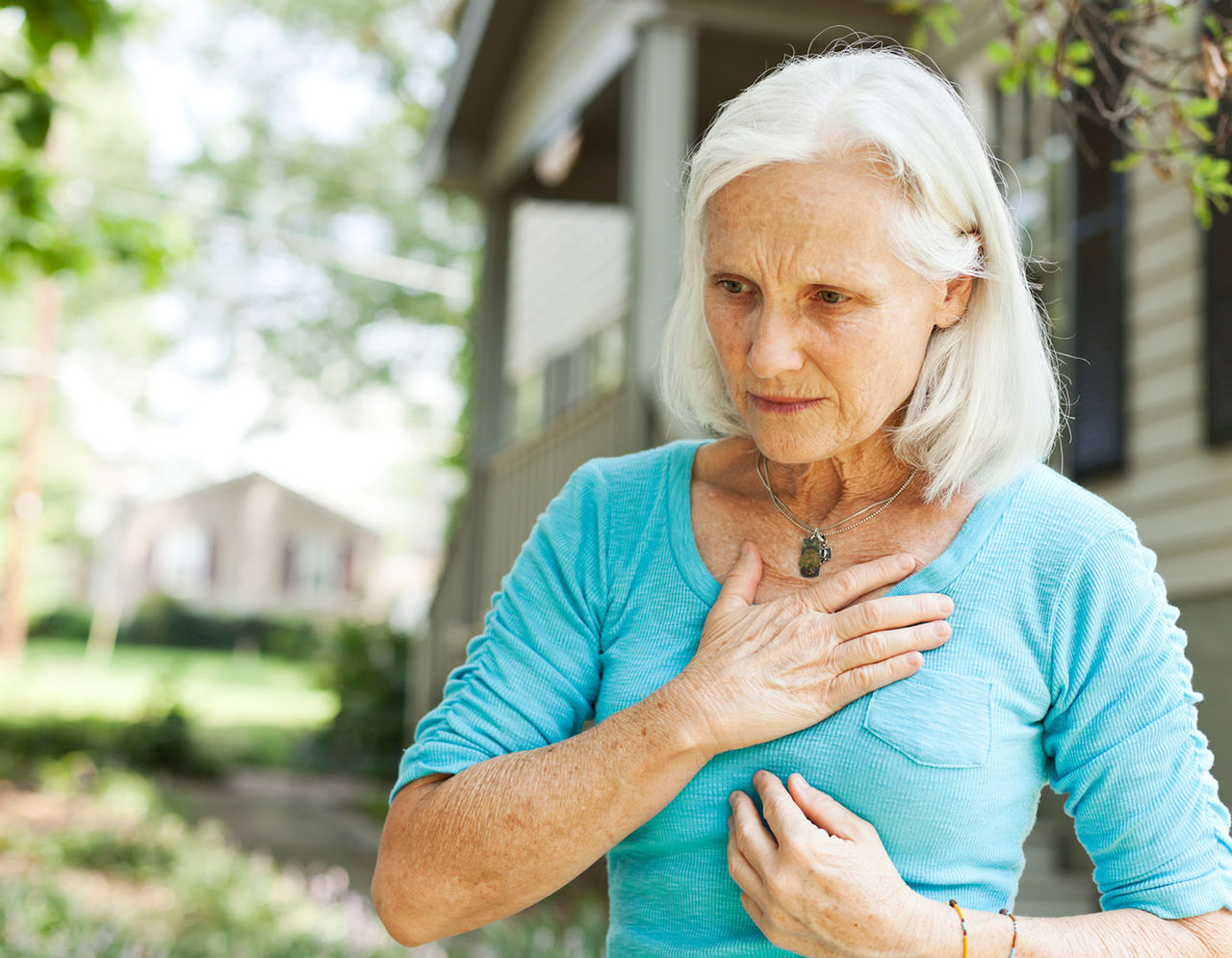 An older woman with her hand on her chest. 