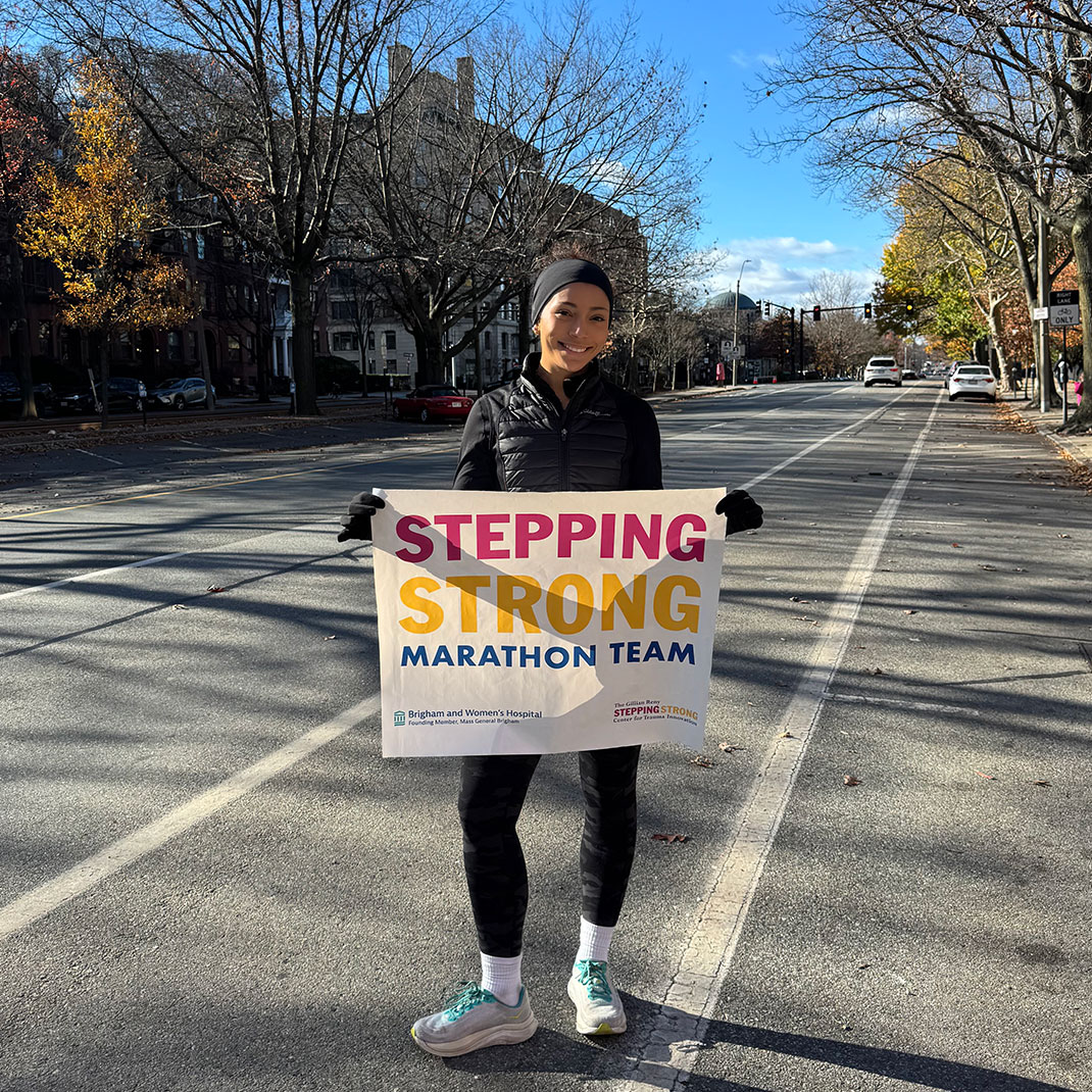 Ashley Panzone holds a sign that reads, Stepping Strong Marathon Team.