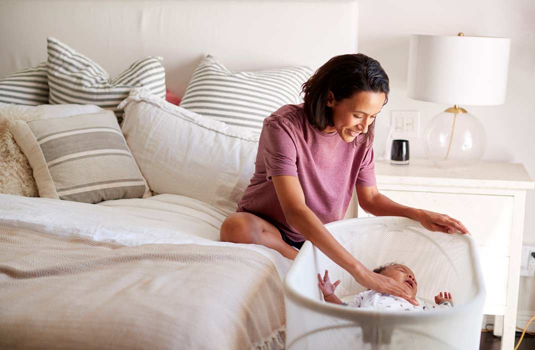 A woman puts her baby's safe sleep crib in her bedroom.