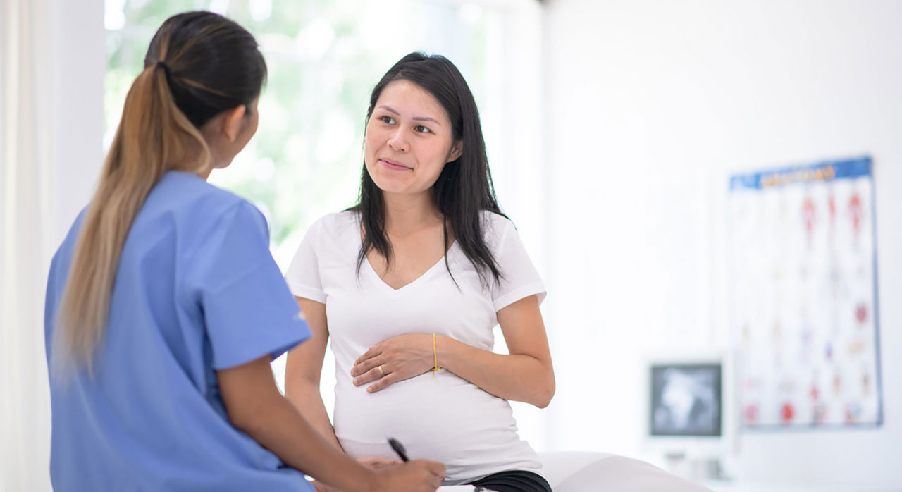 Pregnant woman discusses with practitioner in an exam room