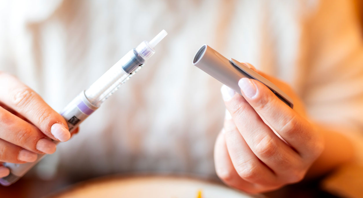 Closeup of a person holding a semaglutide injection pen.