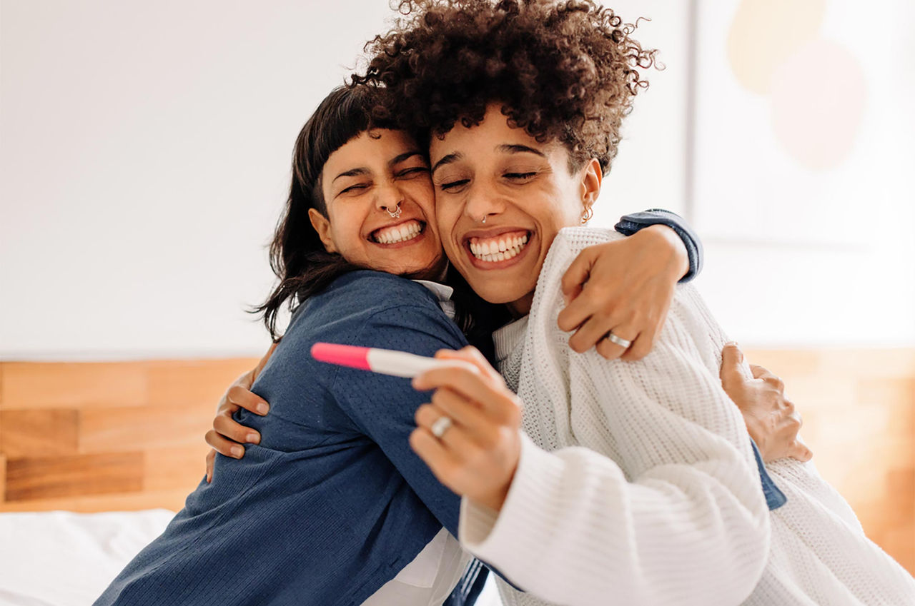 A happy couple embracing each other and holding a pregnancy test
