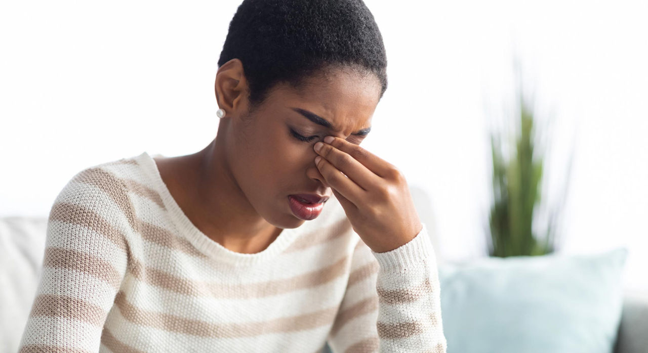 Woman with sinus pressure pain presses fingers on the bridge of her nose