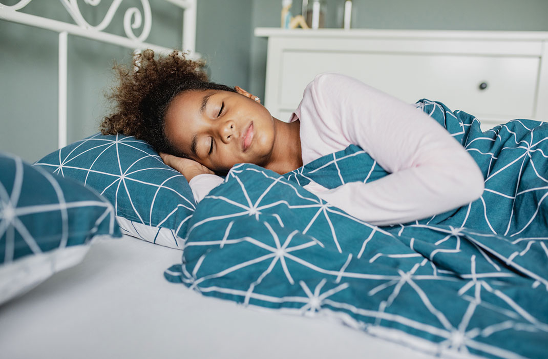 A young girl asleep in bed.