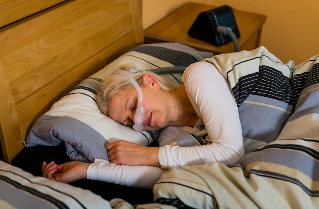 A sleeping older woman wearing a CPAP.