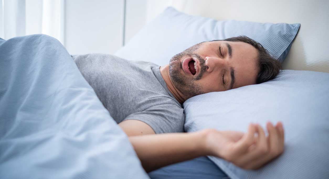 A man snoring in bed.