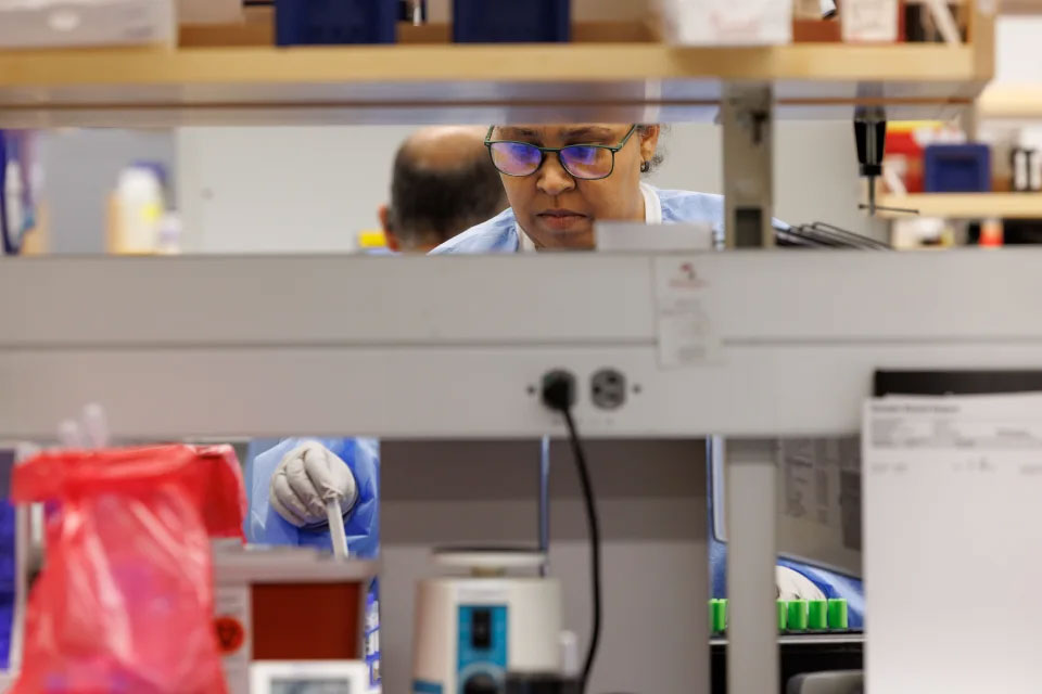 A scientist works at a piece of lab equipment.