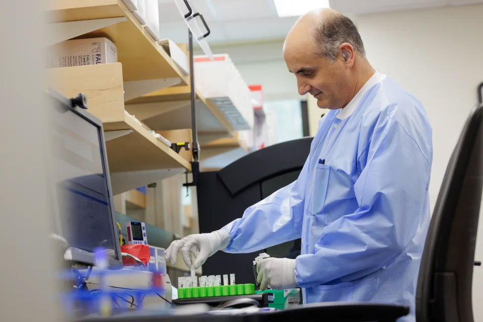 A scientist places sample vials in a green tray.