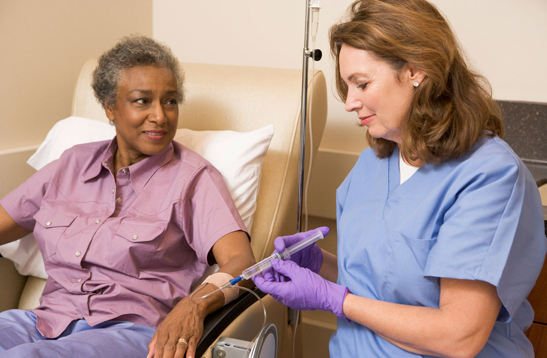 A provider uses an IV to give a patient chemotherapy treatment. 